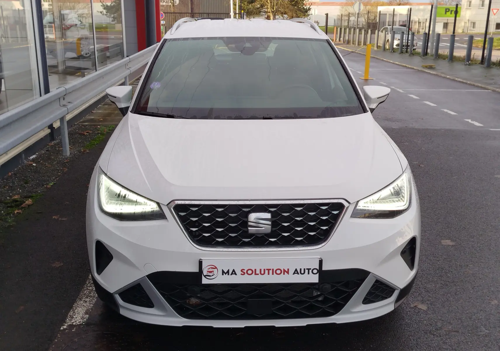 Vue avant d'un SEAT Arona blanc Candy 2023 avec phares LED allumés et calandre noire ajourée.