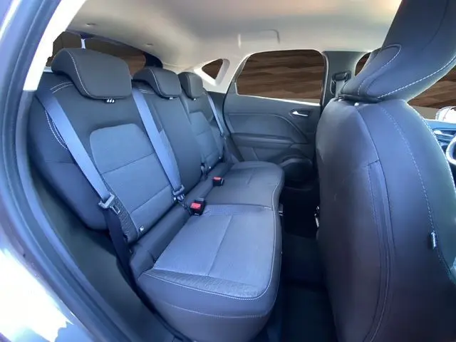 Vue intérieure arrière droite du Renault Captur E-Tech Full Hybrid 145 Evolution 2023, sièges tissu noir et ceintures grises.