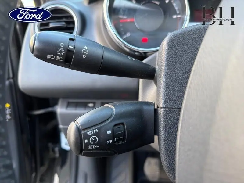 Gros plan sur les commandes au volant d’une Peugeot 3008 noire, avec levier de clignotants et régulateur de vitesse.