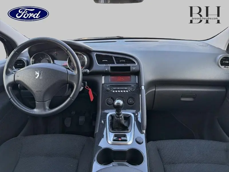 Vue intérieure avant du tableau de bord et volant noir d’un Peugeot 3008 1.6 HDi112 FAP Style de 2012 avec boîte manuelle.