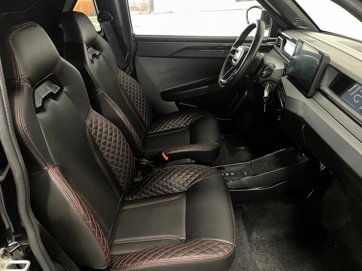 Vue intérieure côté conducteur de la LIGIER JS50 2026 avec sièges noirs surpiqués rouges et tableau de bord moderne.