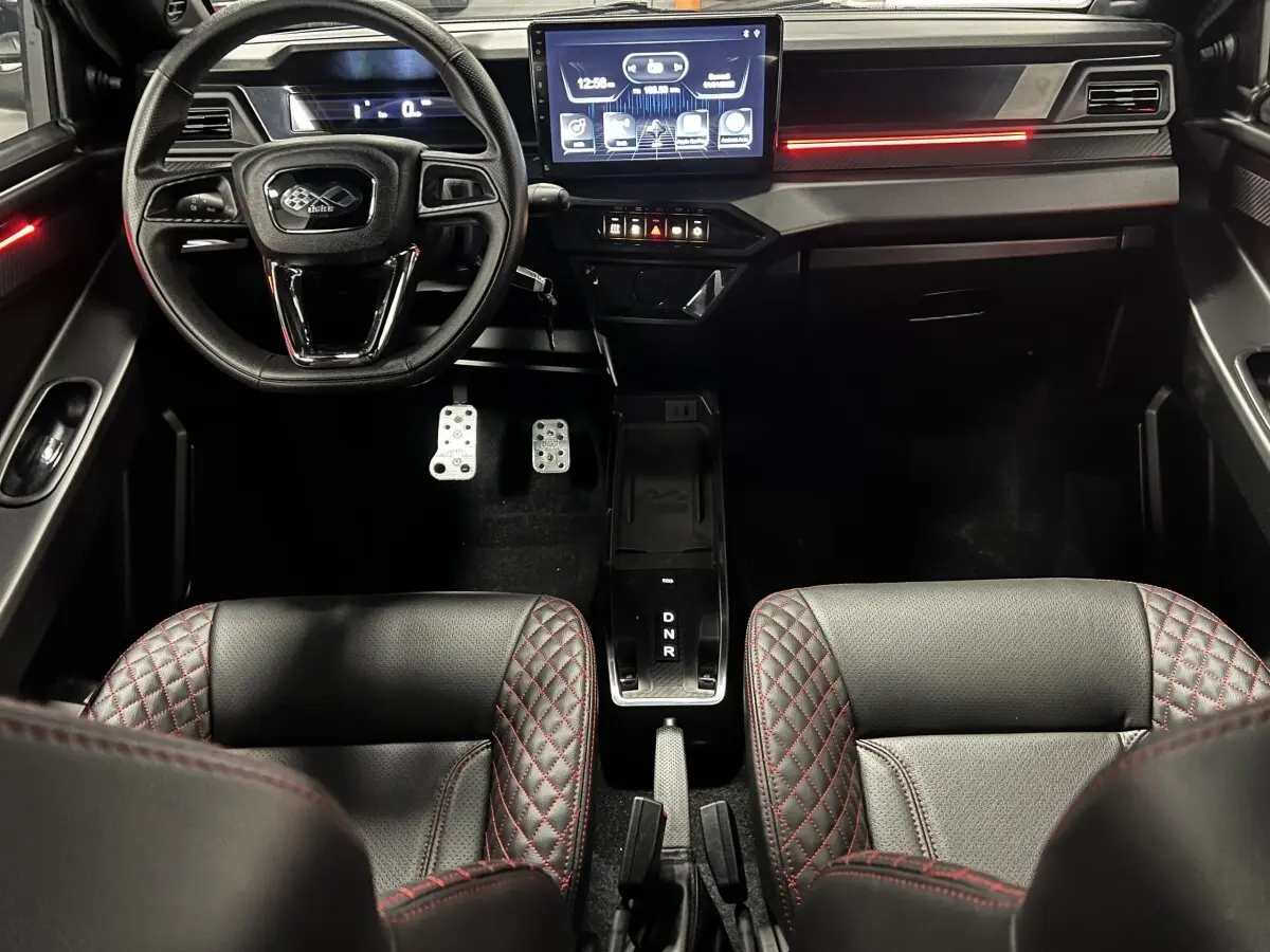 Vue intérieure avant du LIGIER JS50 noir avec sièges Ultimate surpiqués rouges et écran tactile central lumineux.