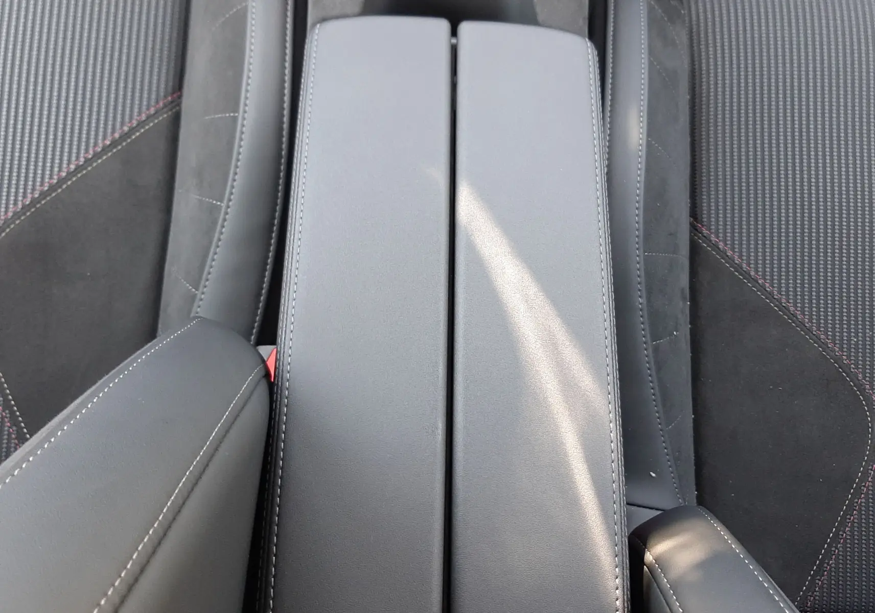 Vue plongeante sur la console centrale en cuir noir et les sièges tissu noir avec surpiqûres rouges du DS4 Cristal Pearl 2024.