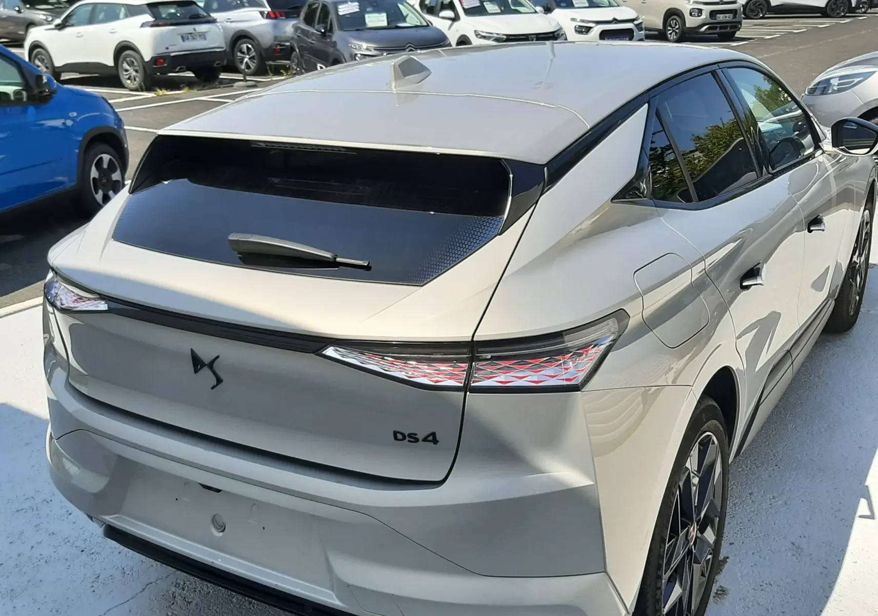Vue 3/4 arrière droite d'une DS4 2024 Cristal Pearl avec feux arrière LED et toit noir brillant en concession.