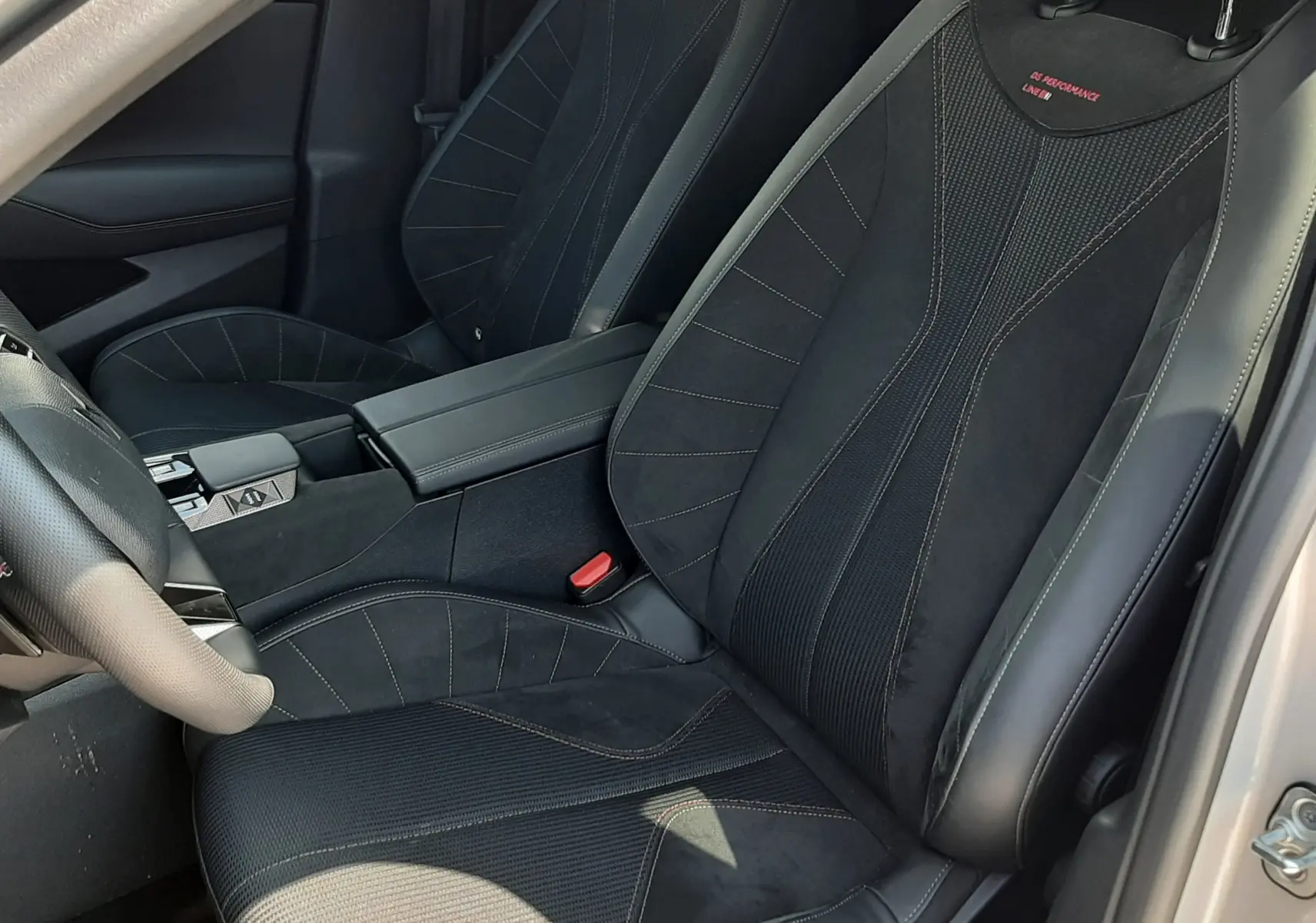 Vue intérieure côté conducteur du DS4 2024, sièges noirs en cuir et alcantara avec surpiqûres rouges et logo Performance Line.