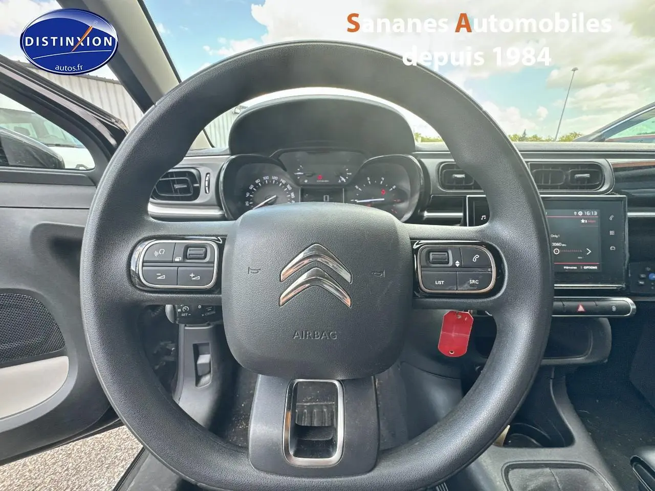 Vue centrée sur le volant de la Citroën C3 noire 2023 avec commandes audio et tableau de bord numérique visible.