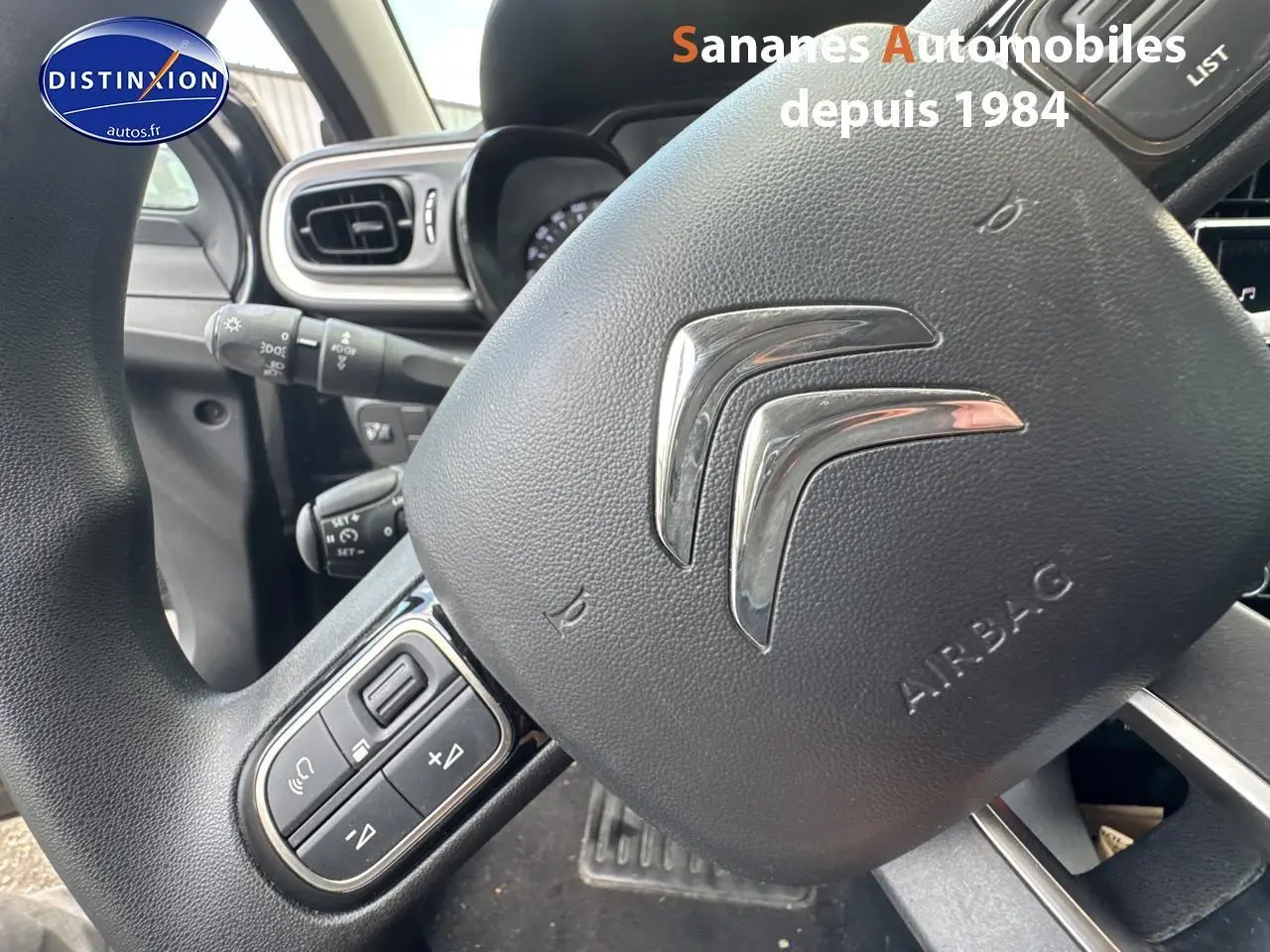 Gros plan sur le volant noir de la Citroën C3 2023 avec commandes audio intégrées côté gauche.