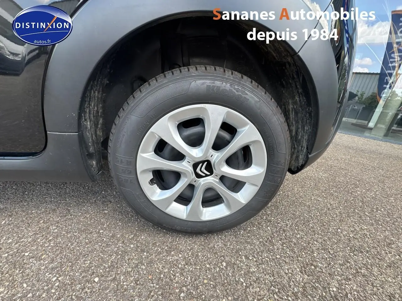 Gros plan sur la roue avant droite d'une Citroën C3 noire 2023 avec jante argentée et logo Citroën central.