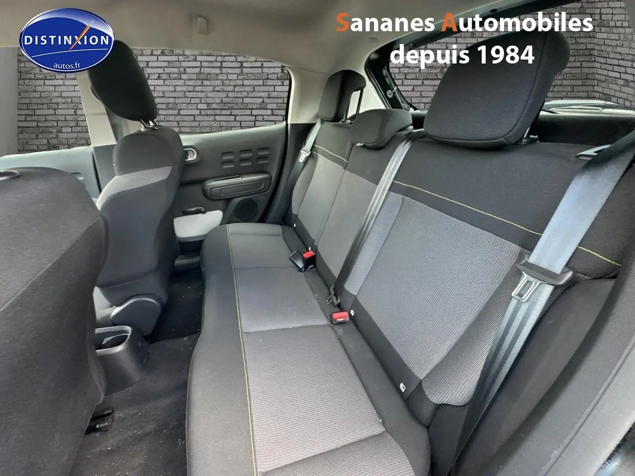 Vue intérieure arrière montrant les sièges arrière en tissu gris et noir avec surpiqûres jaunes d'une Citroën C3 noire 2023.