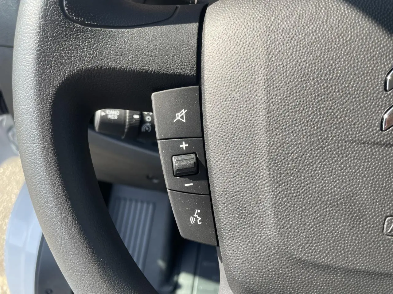 Gros plan sur les commandes de volume et de coupure du son au volant du Citroën Jumper blanc 2023.
