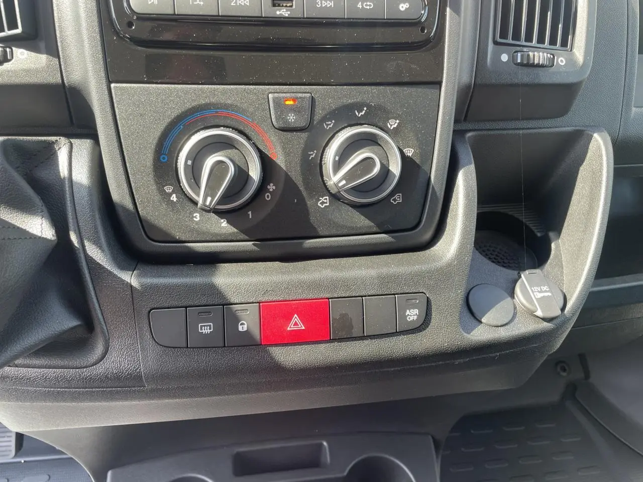 Gros plan sur la console centrale du Citroën Jumper 2023, montrant les commandes de climatisation et boutons de sécurité.