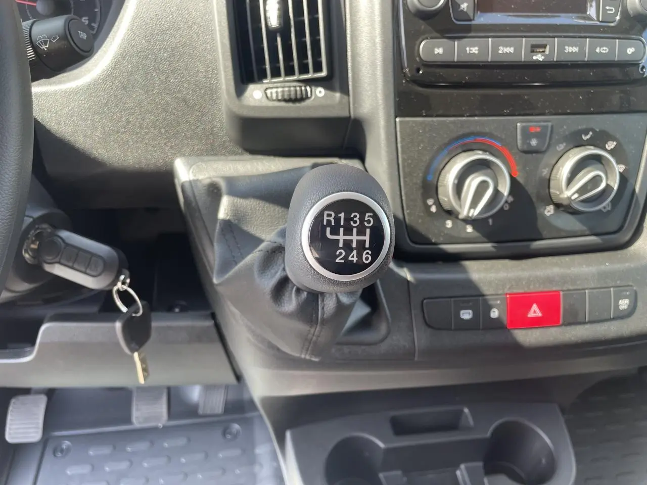Le levier de vitesses manuel en gros plan du tableau de bord du Citroën Jumper blanc 2023 avec commandes de climatisation et radio.