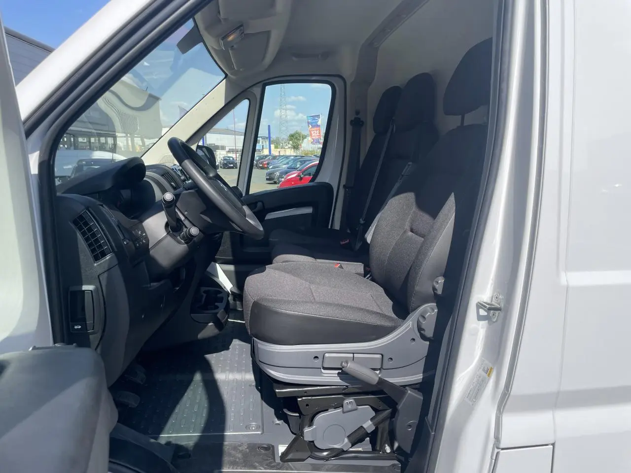 Vue intérieure côté conducteur du Citroën Jumper blanc 2023, montrant les sièges avant et le tableau de bord.