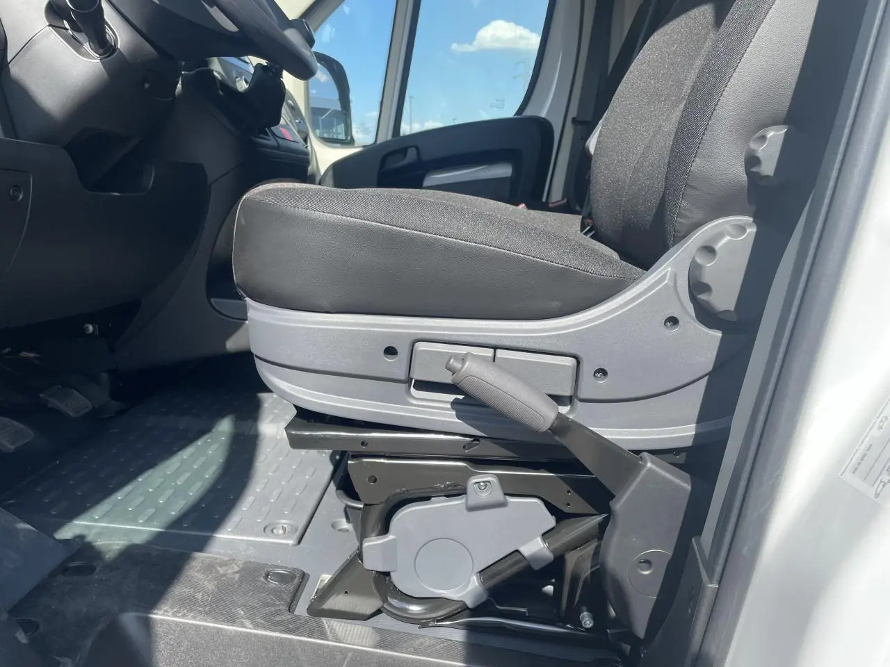 Détail du siège conducteur noir du Citroën Jumper blanc 2023, avec levier de réglage manuel visible côté droit.