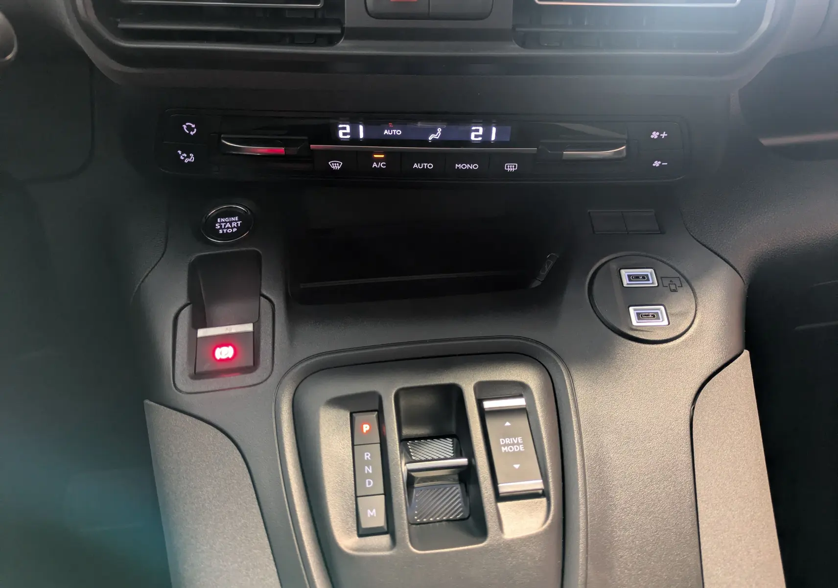 Vue rapprochée du tableau de bord et console centrale noire du Peugeot Rifter gris Artense 2025 avec commandes climatisation et boîte auto.