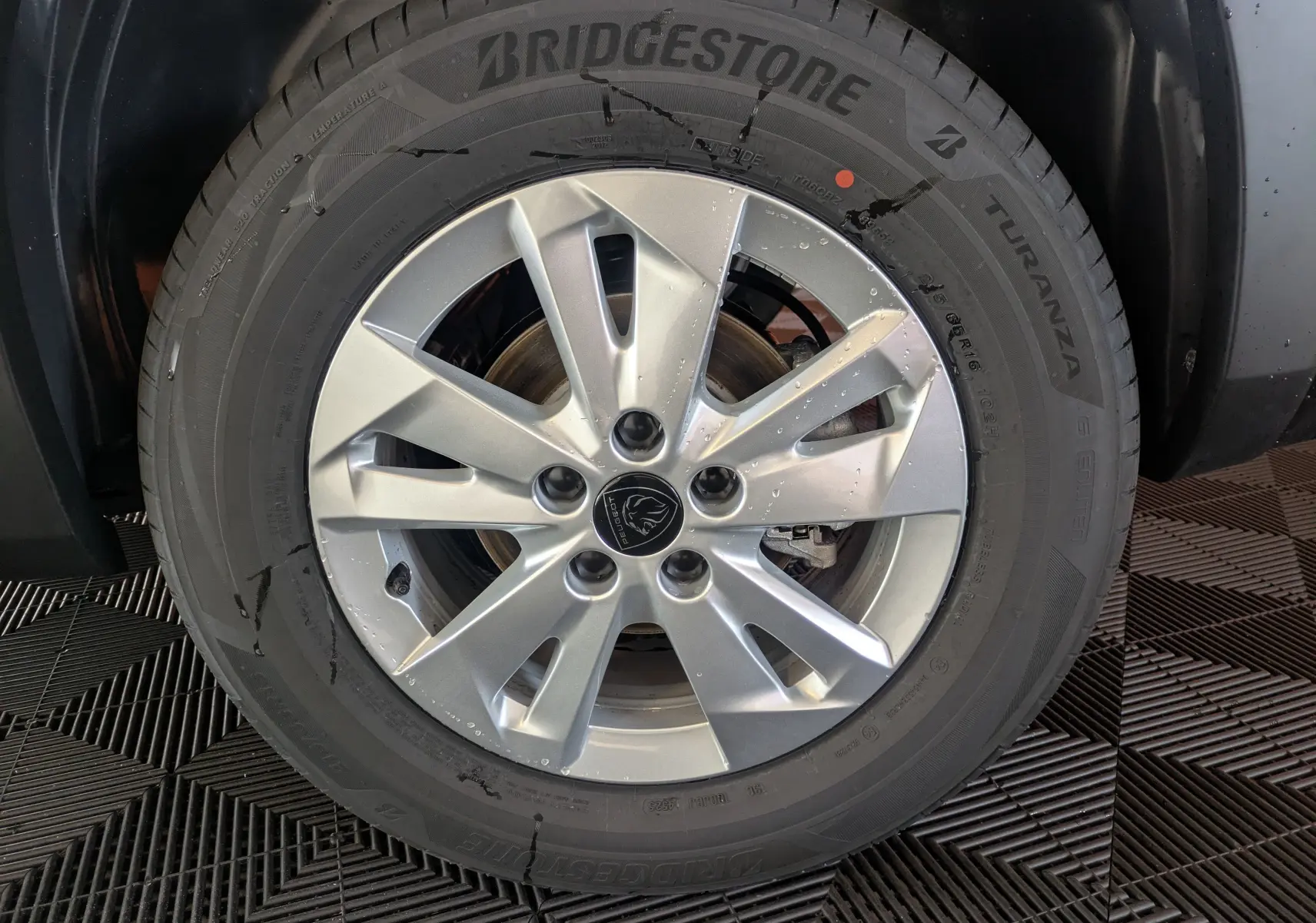 Gros plan sur la roue avant droite du Peugeot Rifter gris Artense, avec jante alliage 16 pouces et pneu Bridgestone Turanza.