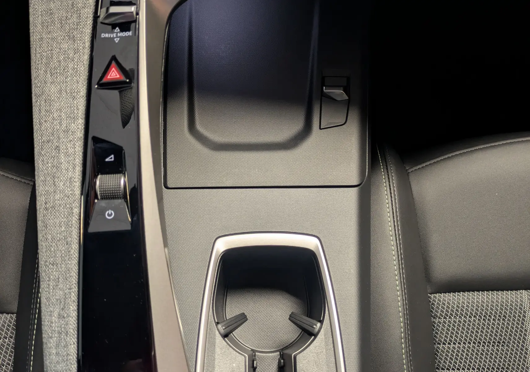 Vue plongeante sur la console centrale noire du Peugeot 3008 hybride 2026 avec porte-gobelets et commandes tactiles.