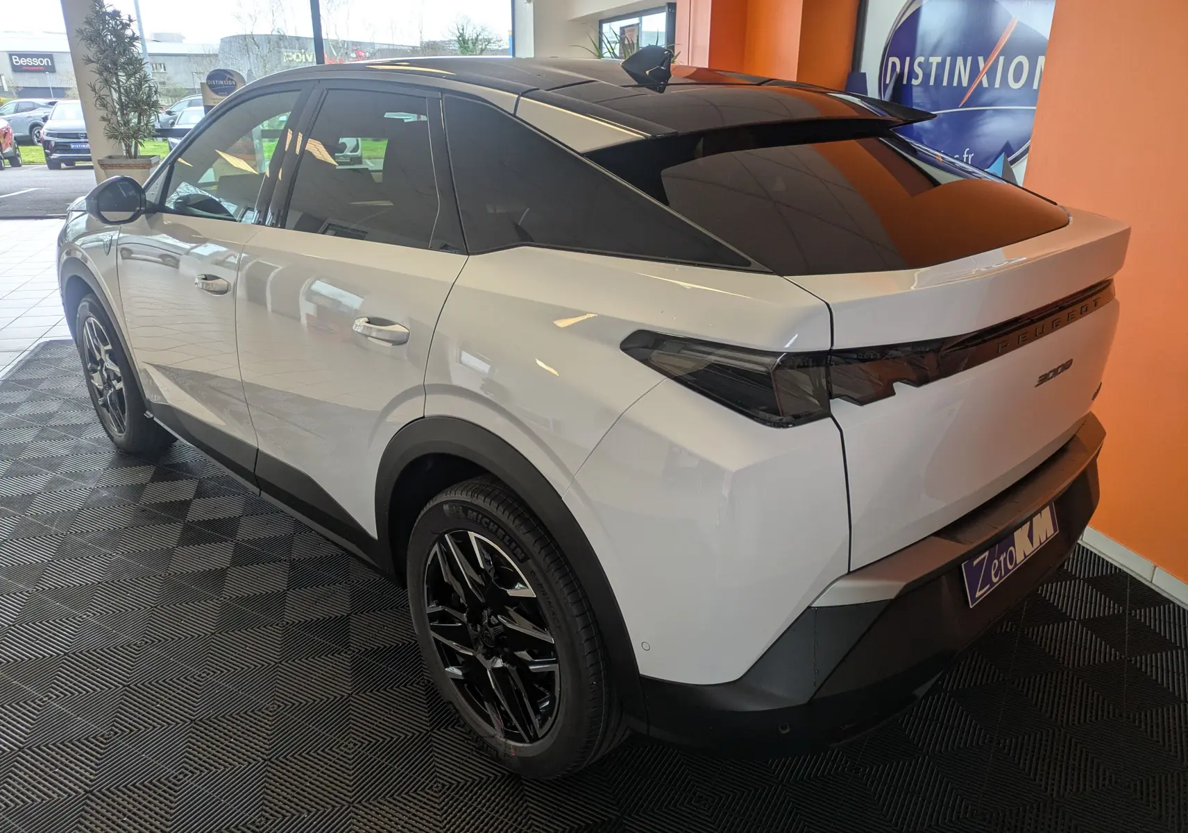 Vue 3/4 arrière droite du Peugeot 3008 blanc Okenite avec toit noir et jantes noires en concession.