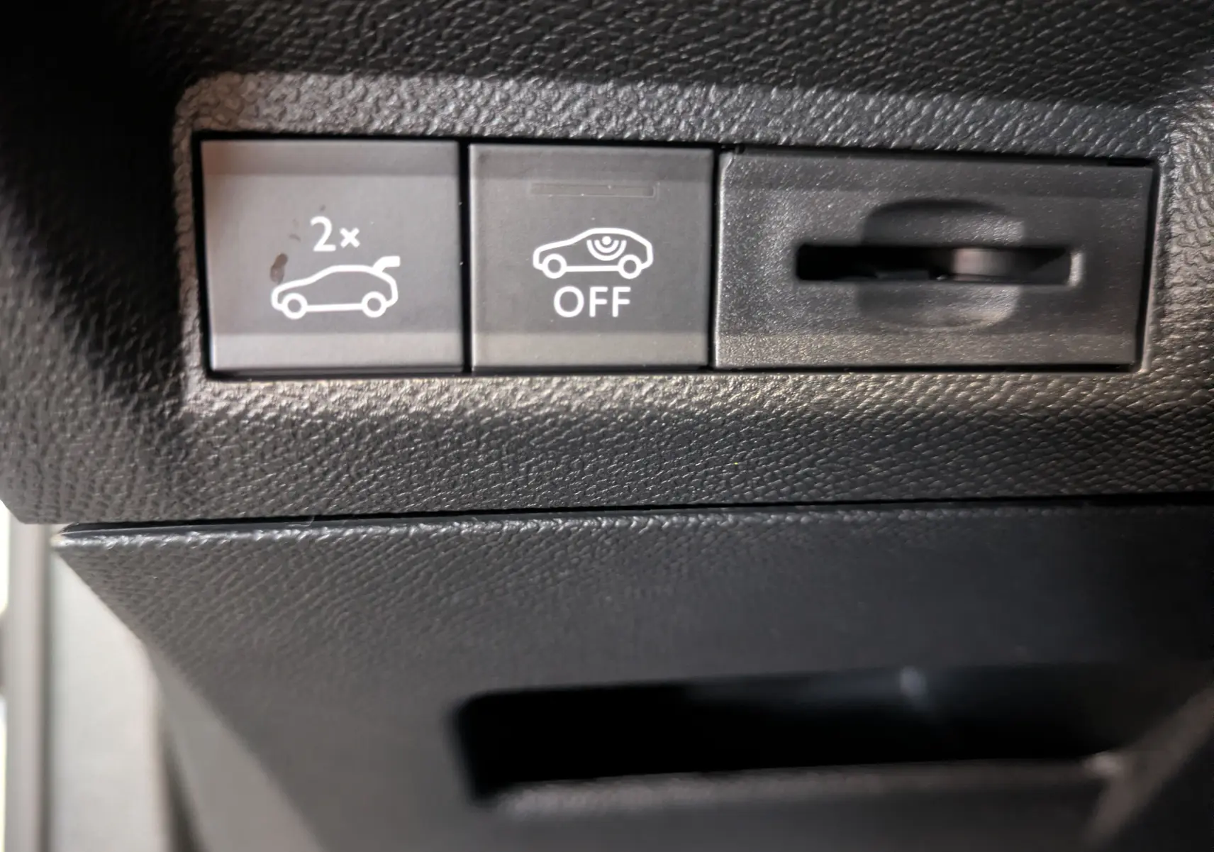 Gros plan sur les boutons de commande intérieurs noirs du Peugeot 3008, avec pictogrammes blancs de coffre et capteurs.
