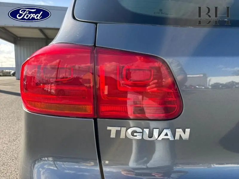 Gros plan sur le feu arrière gauche et le logo Tiguan d’un Volkswagen Tiguan gris Crypton, vue arrière côté gauche.