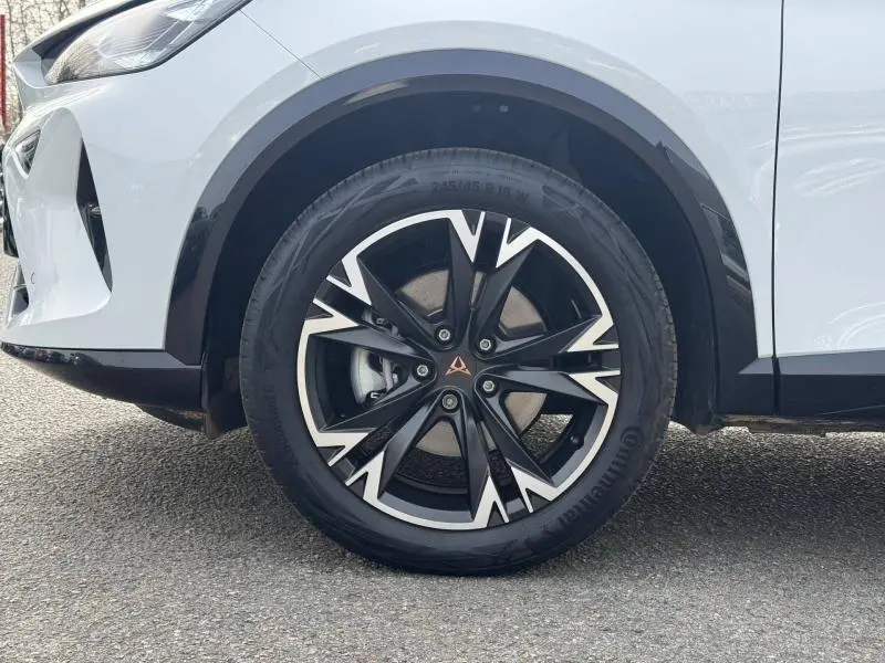 Gros plan sur la roue avant gauche d'une CUPRA Formentor blanc Nevada métallisé avec jante noire et argentée au design dynamique.