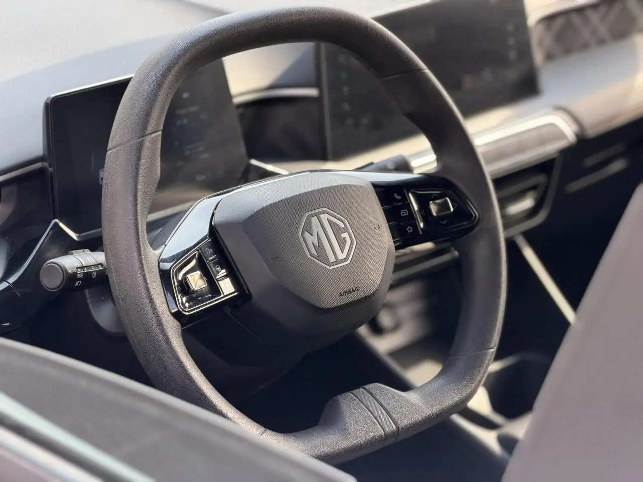 Gros plan sur le volant multifonction noir du MG3 1.5 Hybrid+ 195 Comfort avec tableau de bord numérique flou.