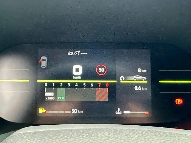 Tableau de bord numérique du Dacia Duster blanc 2025 affichant vitesse, régime moteur et alertes de conduite.