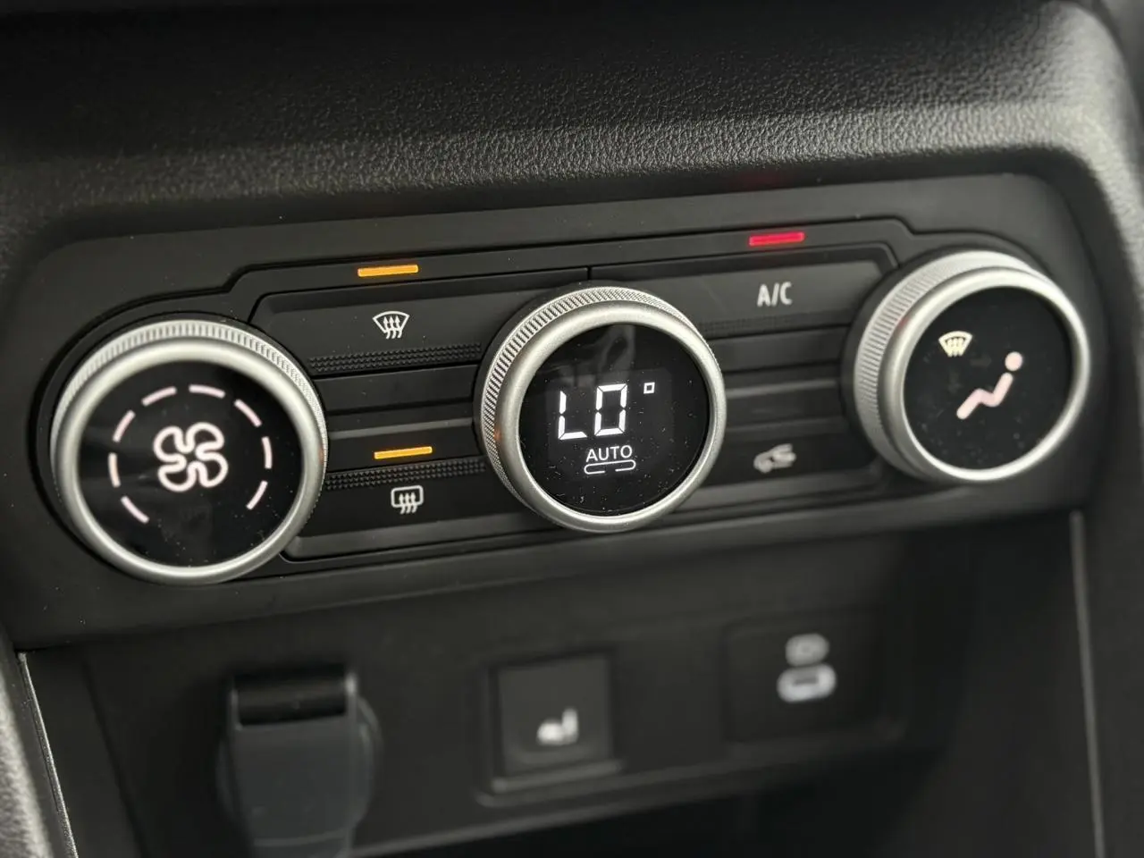 Gros plan sur les commandes de climatisation automatique de la Dacia Sandero Stepway gris schiste, affichant 16°C.