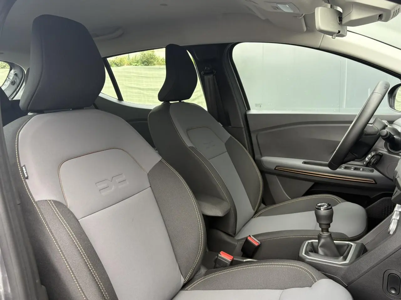 Vue intérieure côté droit des sièges avant gris clair et foncé de la Dacia Sandero Stepway TCE 110 Extrême 2025.