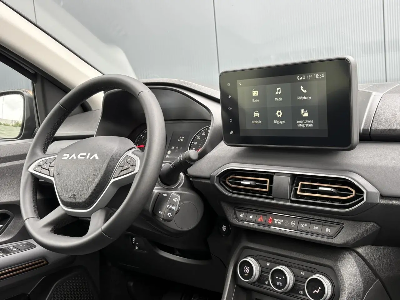 Intérieur de la Dacia Sandero Stepway 2025 en gris, vue de face sur le volant et l'écran tactile central.