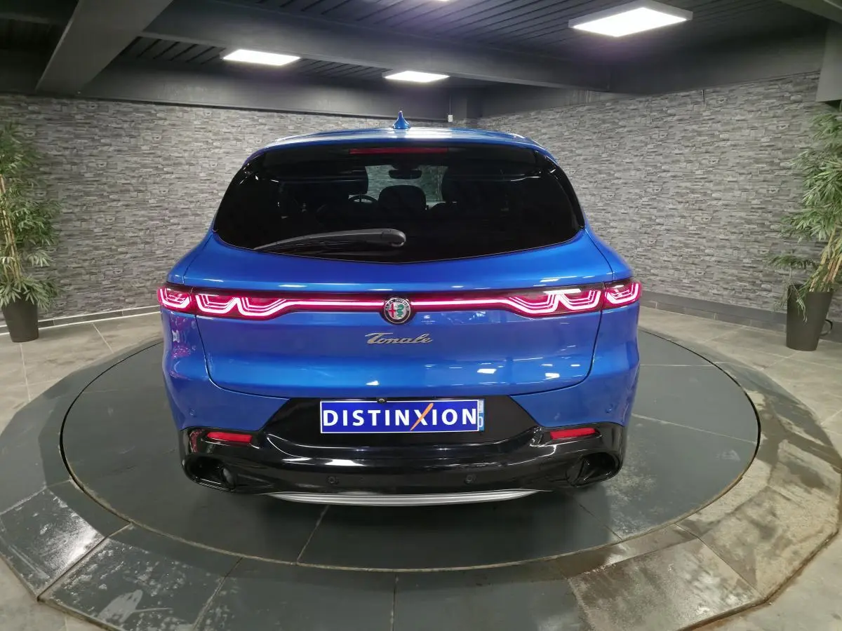 Vue arrière d'une Alfa Romeo Tonale 2024 bleue métallisée avec feux arrière LED et logo central lumineux.