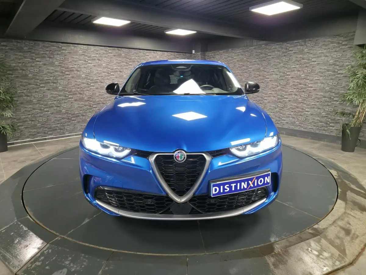Vue frontale d'une Alfa Romeo Tonale 2024 bleu métallisé avec calandre caractéristique et phares LED allumés.