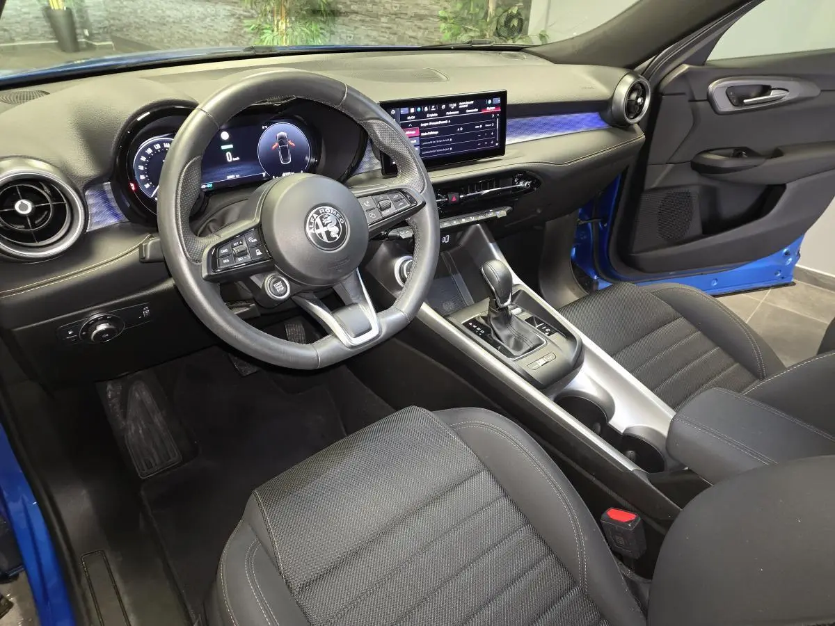 Intérieur de l'Alfa Romeo Tonale bleu, vue côté conducteur, volant sport cuir et tableau de bord digital.