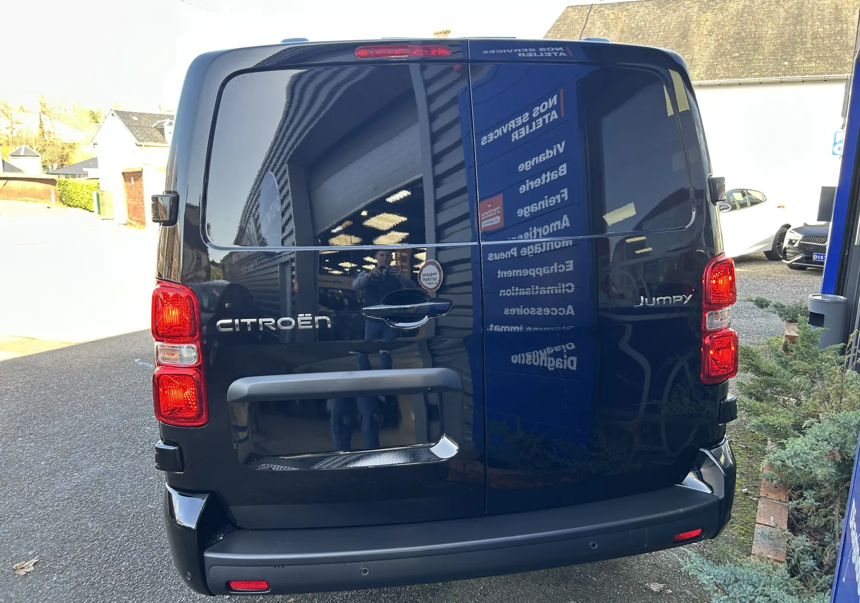 Vue arrière d'un Citroën Jumpy cabine approfondie noir, avec portes arrière vitrées et feux rouges allumés.