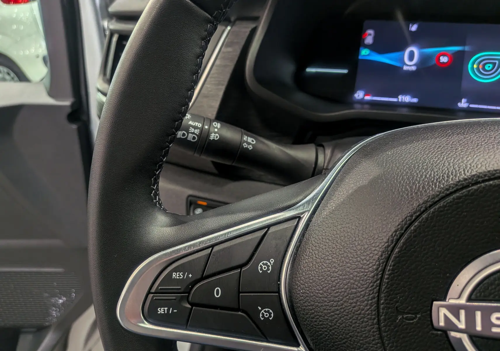 Gros plan sur le volant noir et les commandes de régulateur de vitesse du Nissan Primastar Combi 2026, tableau de bord digital visible.