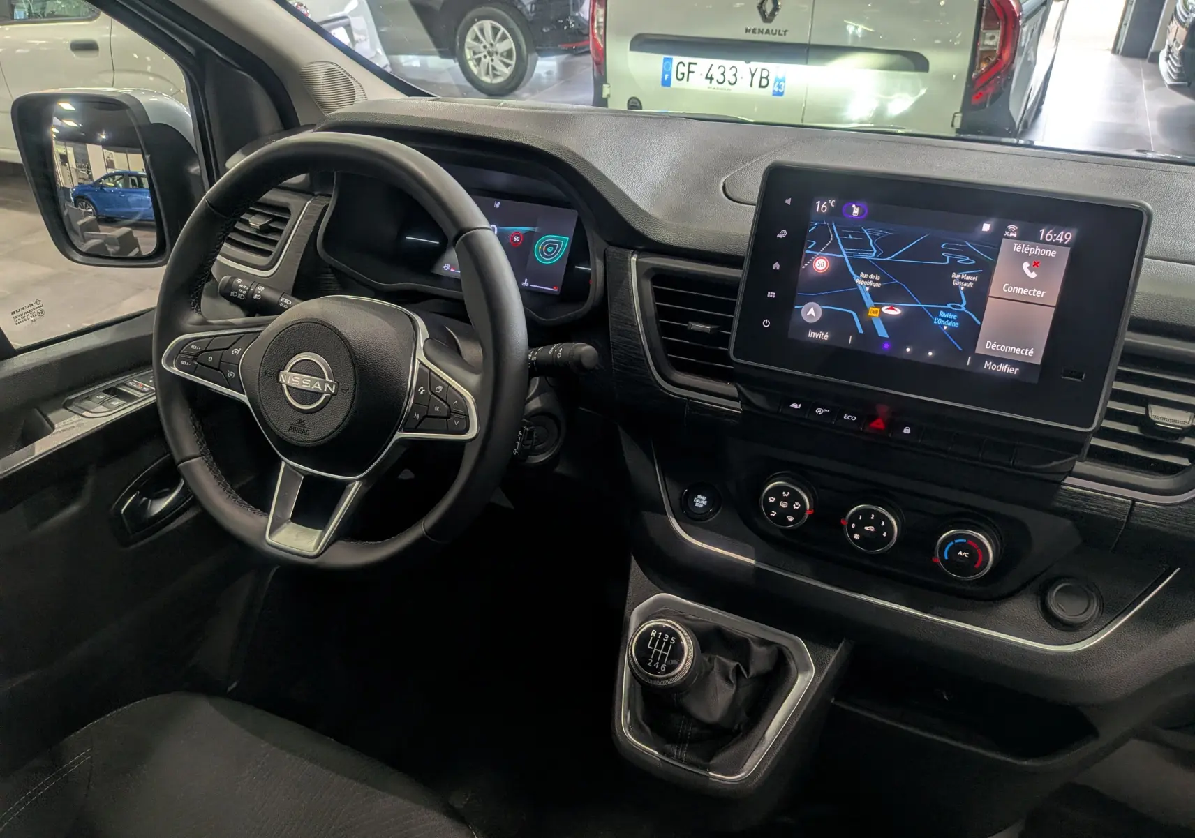 Vue intérieure du poste de conduite du Nissan Primastar Combi 2026, avec volant multifonction, écran tactile et levier de vitesses manuel.