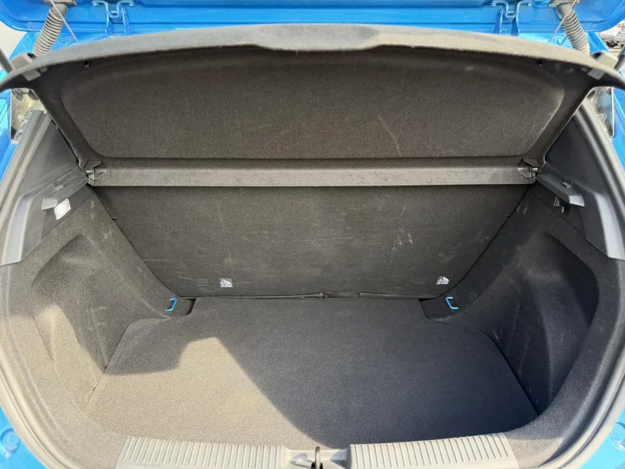 Coffre ouvert vu de l'arrière d'une MG3 1.5 Hybrid+ 195 Comfort bleu Como, intérieur noir et espace de rangement visible.