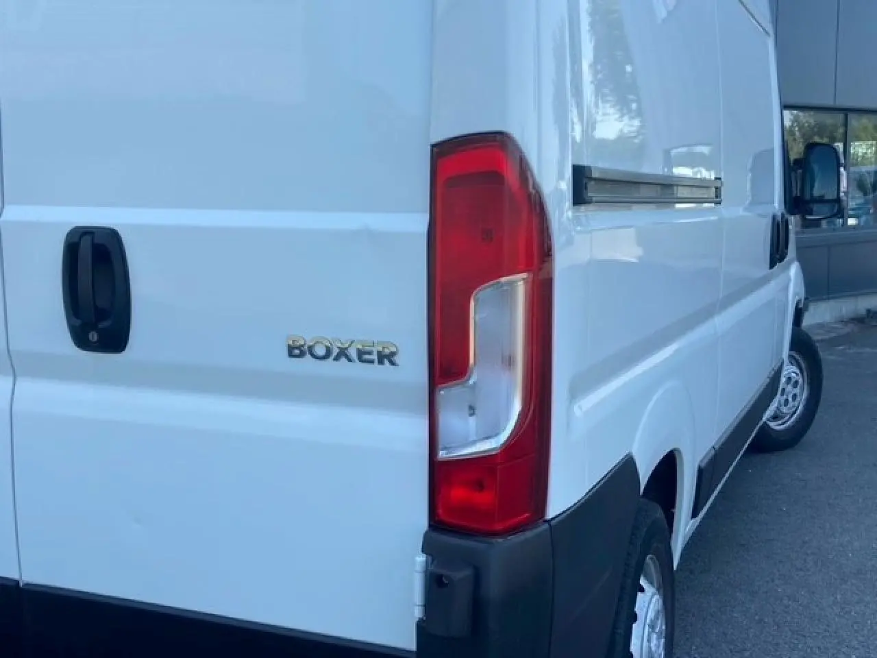 Vue arrière droite du Peugeot Boxer Fourgon blanc montrant le feu arrière et le logo BOXER sur la porte.