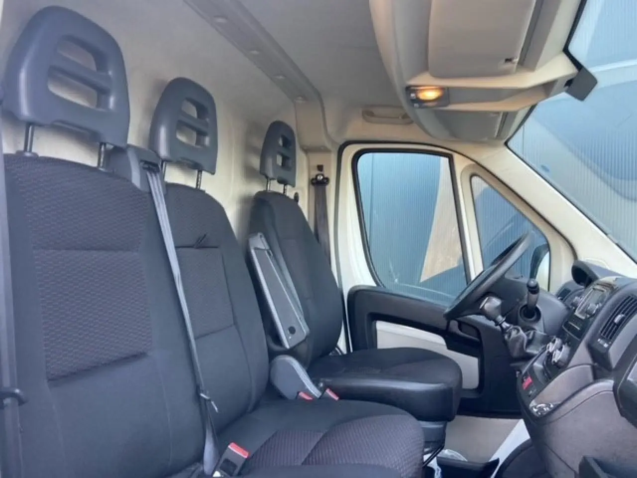 Intérieur du Peugeot Boxer Fourgon 2019 vu côté droit, montrant les sièges noirs et le tableau de bord avec boîte manuelle.