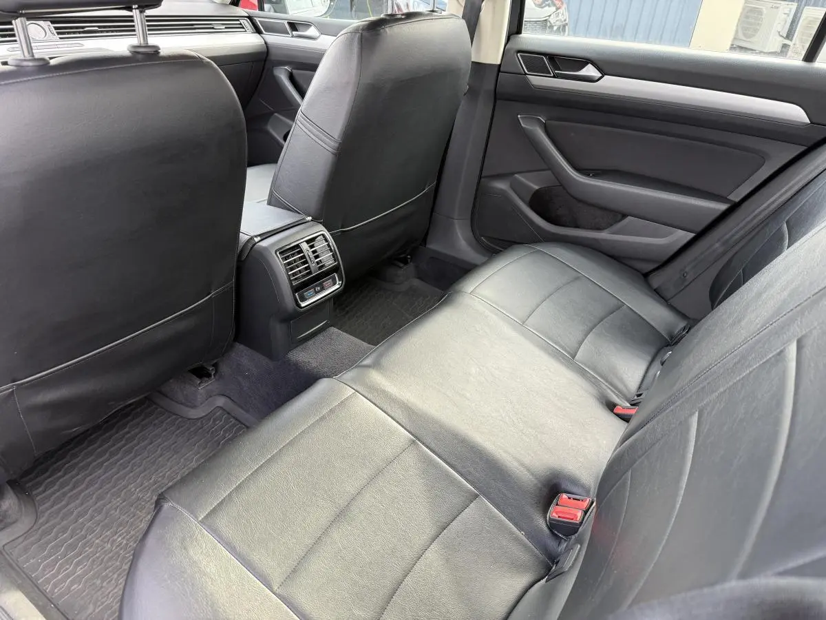 Vue intérieure arrière côté droit de la Volkswagen Passat 2018 avec sièges en cuir noir et aérateurs centraux visibles.