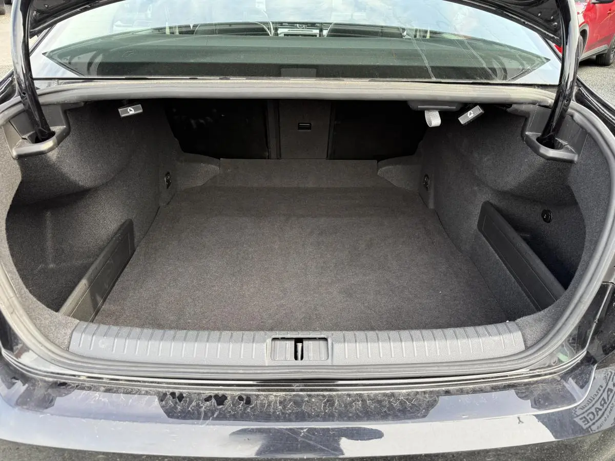 Coffre ouvert d'une Volkswagen Passat noire 2018, vue arrière montrant l'espace de chargement vide et moquetté.