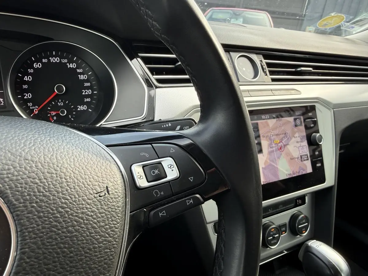 Intérieur de Volkswagen Passat 2018 vu côté conducteur, volant cuir et écran de navigation affichant une carte.