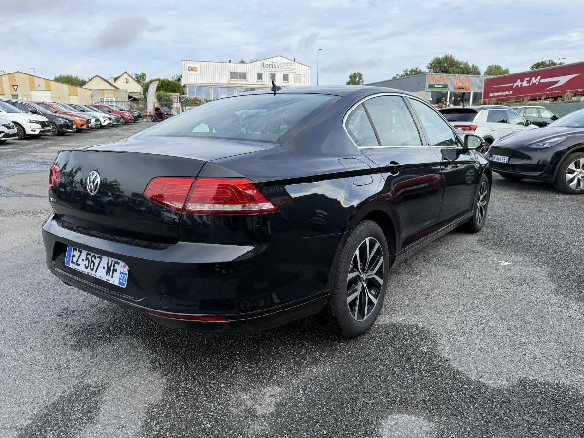 Volkswagen Passat noire vue 3/4 arrière droit, feux arrière LED et jantes alliage 16 pouces visibles.