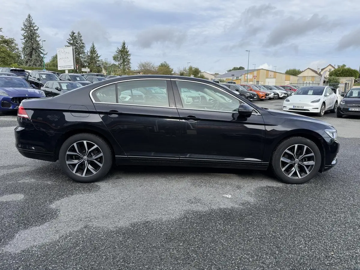 Profil côté gauche d'une Volkswagen Passat noire 2018 avec jantes alliage et vitres teintées sur parking.