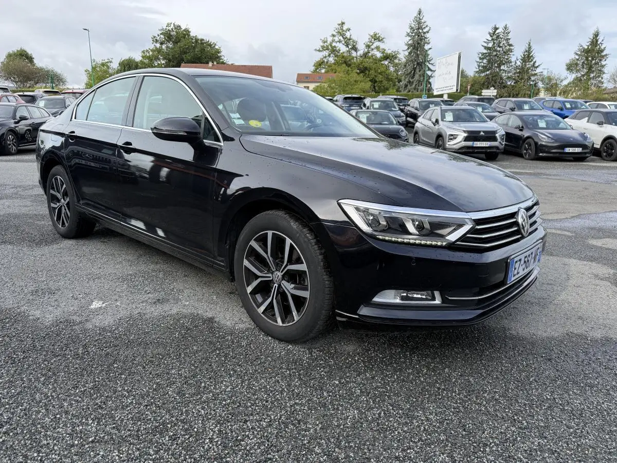 Volkswagen Passat noire vue 3/4 avant droit, avec jantes alliage et calandre chromée sur parking.