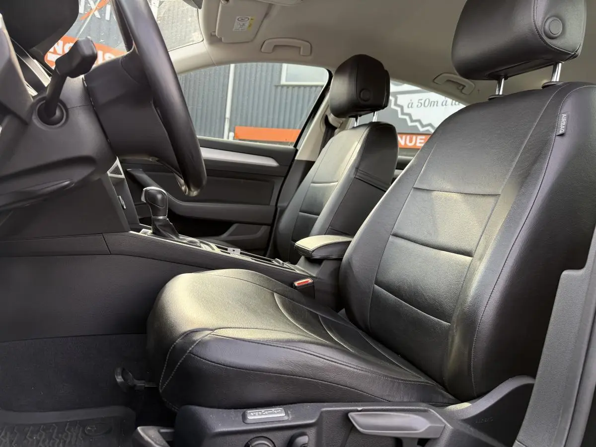 Intérieur avant de la Volkswagen Passat 2018 noir, vue côté conducteur montrant sièges en cuir et console centrale.