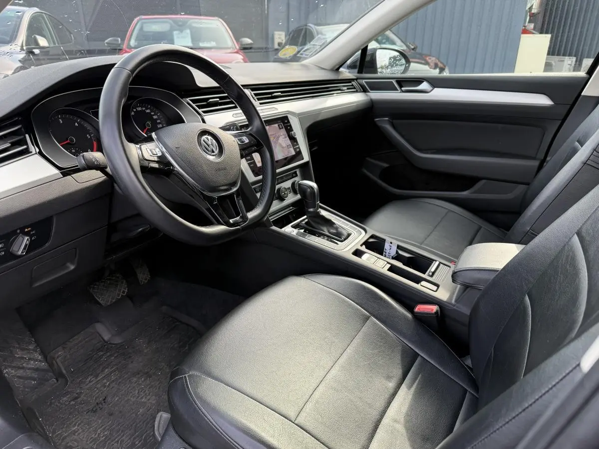 Intérieur avant droit de la Volkswagen Passat 2018 noir, volant cuir multifonction et console centrale avec boîte auto.