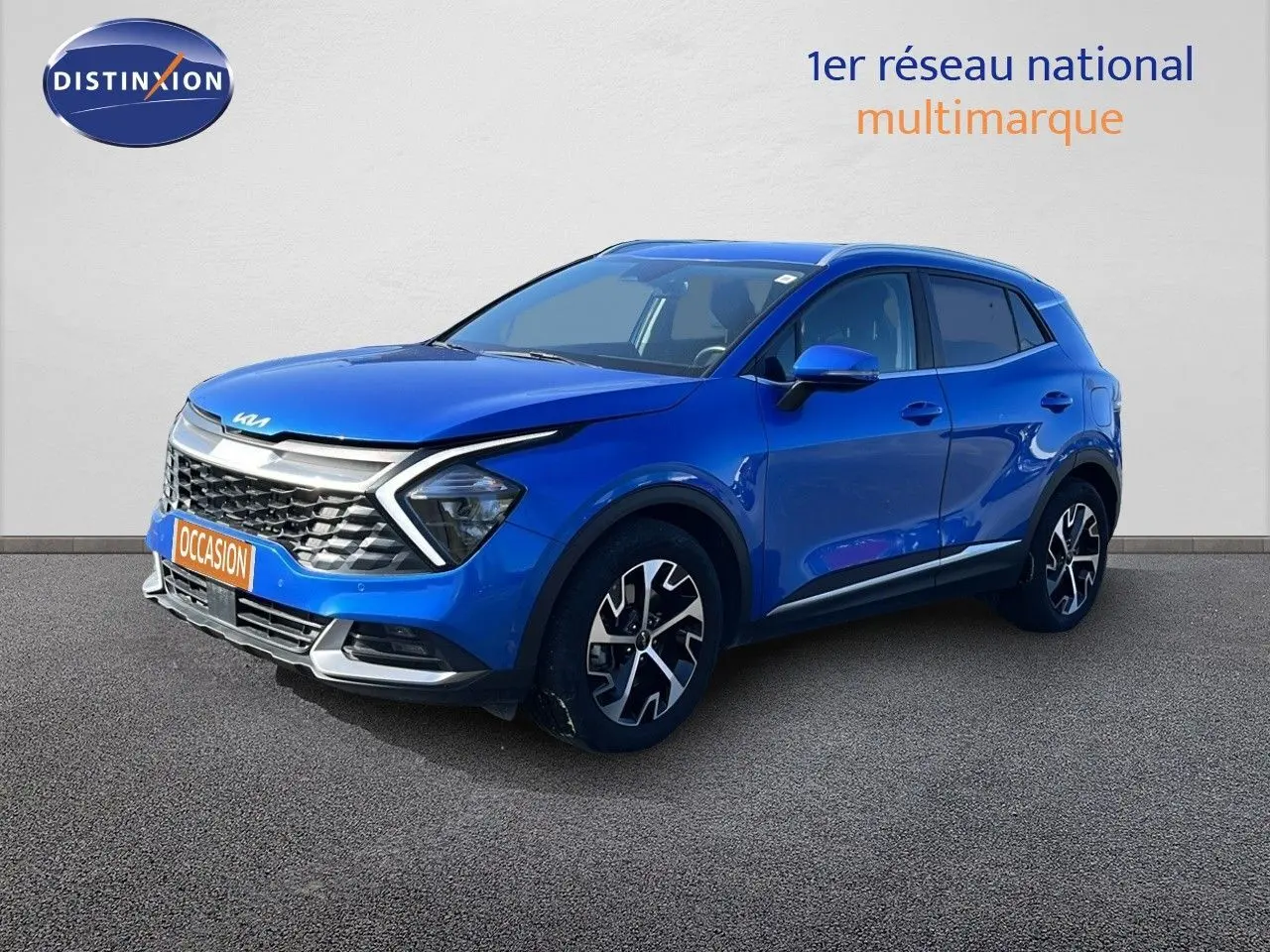 Vue 3/4 avant droite d'un KIA Sportage bleu fusion métal 2022 avec calandre distinctive et jantes noires stylisées.