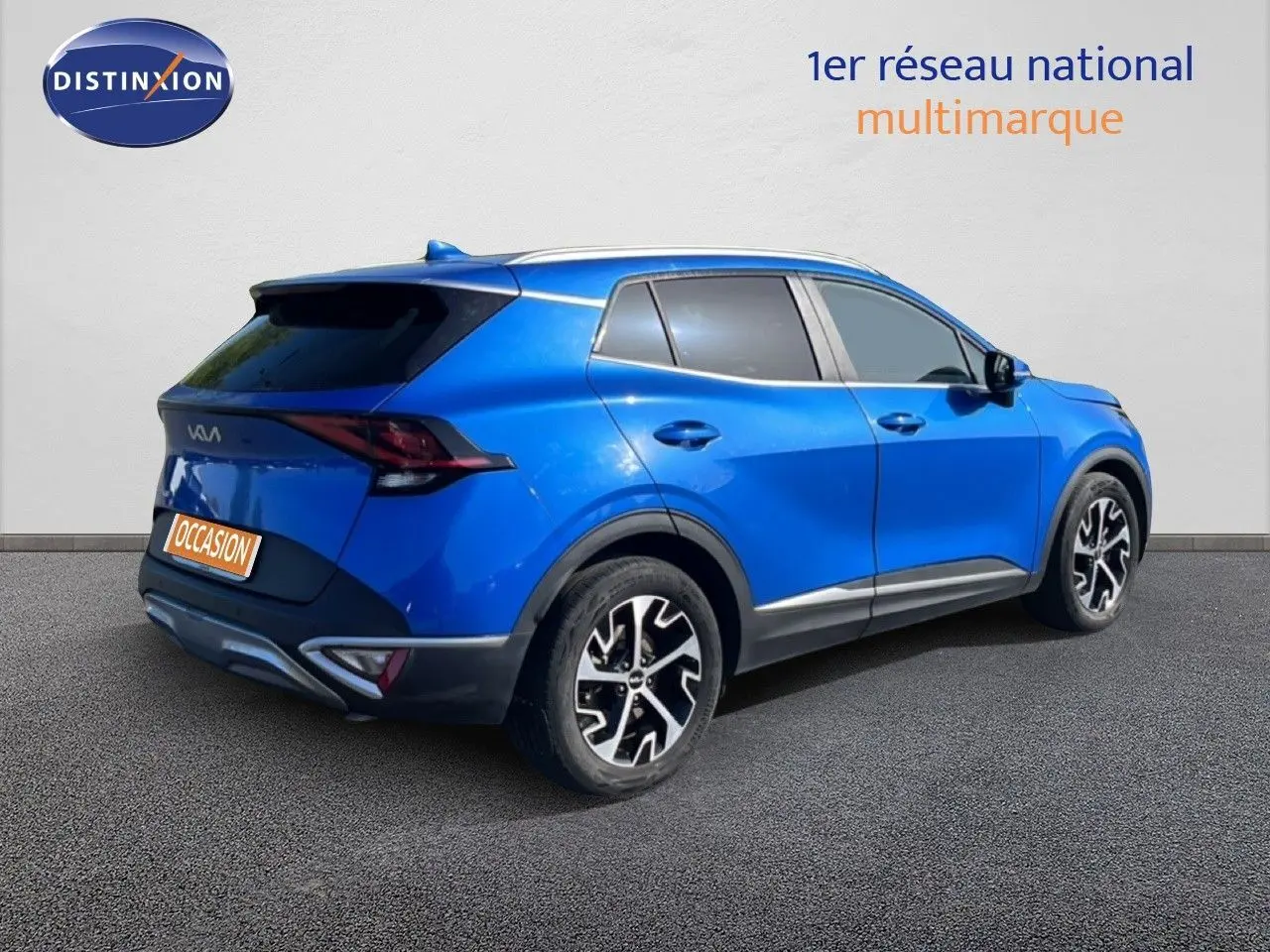 Vue 3/4 arrière droite d'un Kia Sportage bleu fusion métal avec jantes alliage noires et détails chromés.