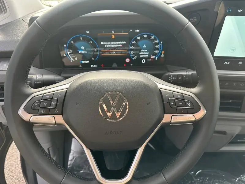 Vue rapprochée du volant cuir multifonction et du tableau de bord numérique du Volkswagen Transporter gris 2025.